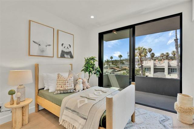 Bright bedroom with a wood bed frame and sliding doors to a balcony with palms