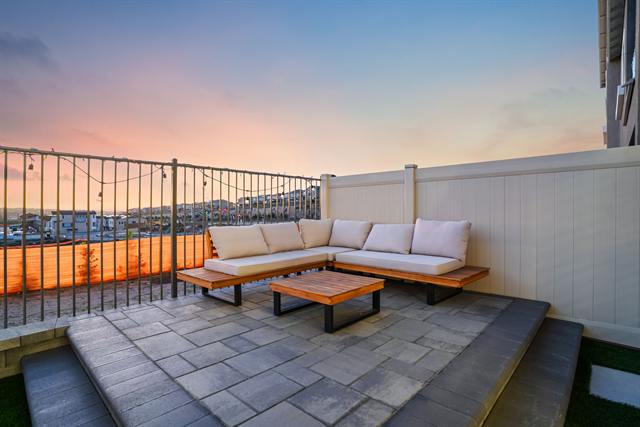 Enclosed patio with outdoor seating and a pink sunset sky