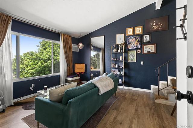 Living room with a dark teal accent wall, a green sofa and a large window